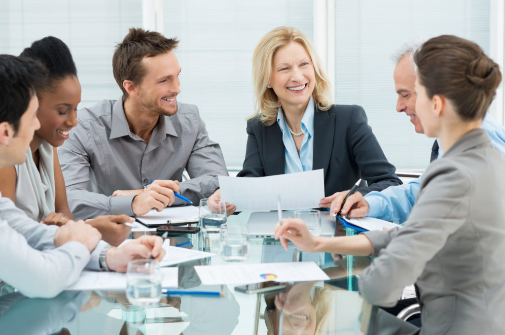 Group Of Happy Coworkers Discussing In Conference Room and no one can tell who is wearing invisalign clear braces 